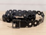 un gros plan d'une ceinture noire posée sur une table en bois