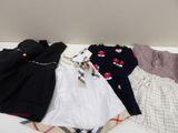 a pile of baby clothes on a bed with a blanket