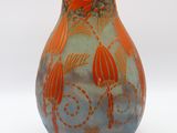 a small vase with orange flowers on it on a white surface