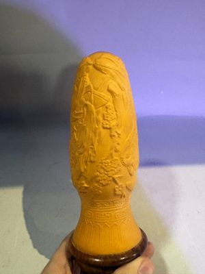 someone is holding a yellow vase in their hand on a white surface