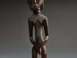 une statue en bois d'un homme avec un chapeau sur la tête