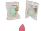 two bags of sponges and a pink sponge on a white background