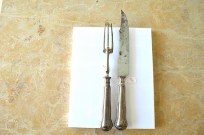 un couteau et une fourchette posés sur un morceau de papier, sur une table