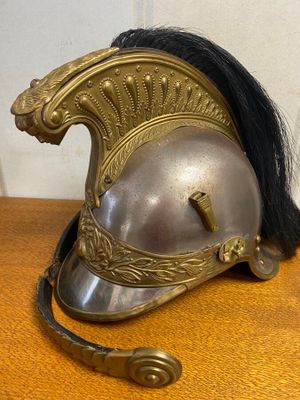 un casque argenté orné de cheveux noirs, posé sur une table en bois