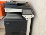 une imprimante multifonction posée par terre à côté d'une pile de livres
