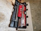 a box of tools sitting on the floor next to a piece of wood