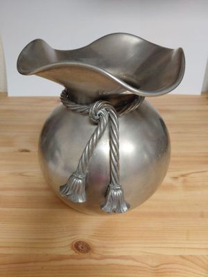 a silver vase with a rope wrapped around it on a wooden table