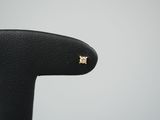un gros plan sur une paire de boucles d'oreilles en or posées sur une chaise noire