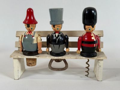 three figurines sitting on a bench on a white background