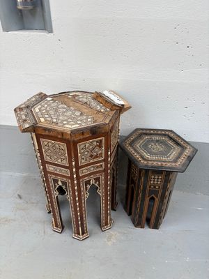 deux tables et un tabouret posés à même le sol devant un mur