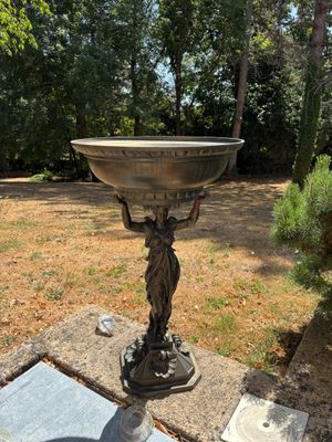 a statue of a woman holding a bowl on top of a pedestal