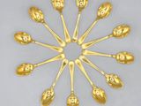six gold spoons arranged in a circle on a white surface