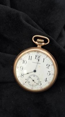 une montre de poche en or posée sur un tissu noir