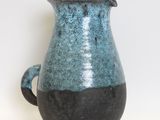 a blue and black vase sitting on a white surface