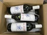 four bottles of wine in a cardboard box on a table