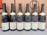 six bouteilles de vin sont alignées sur une table