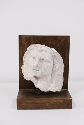 une sculpture blanche représentant le visage d'une femme, posée sur un socle en bois