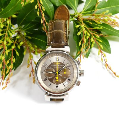 a close up of a watch on a table with flowers
