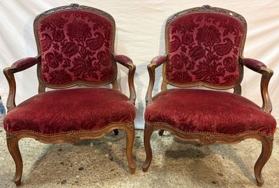 pair of red upholstered chairs with ornate carved arms