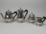 three pieces of silver tea and coffee set on a white surface