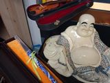 a statue of a smiling buddha sitting in a suitcase
