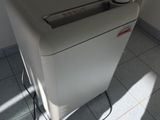 une déchiqueteuse à papier blanche posée sur un sol carrelé