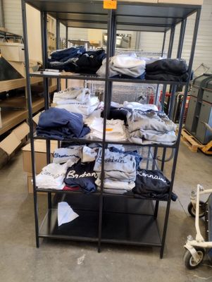 un présentoir de t-shirts et d'autres articles dans un entrepôt
