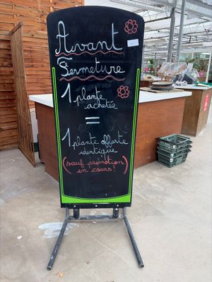 a chalk board with writing on it in front of a building