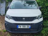 une camionnette blanche garée devant une clôture