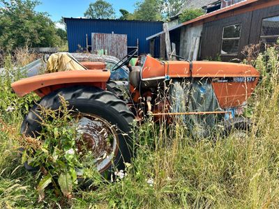 un tracteur orange qui est garé dans l'herbe
