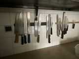 many knives hanging on the wall in the kitchen