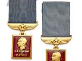 Deux médailles et une médaille sont exposées sur un support blanc