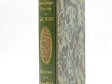 an old book with a green cover on a white surface