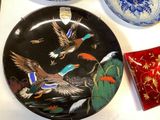 a plate with a painting of birds on it next to other plates
