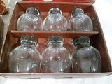 six bocaux en verre vides dans une boîte posée sur une table