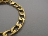 gros plan d'un bracelet en chaîne en or sur une surface grise