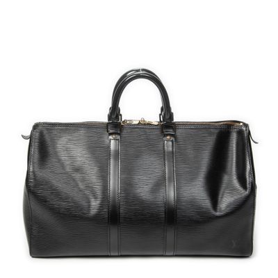 un sac de voyage noir posé sur une surface blanche