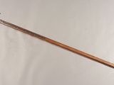 a wooden stick with a metal handle on a white wall