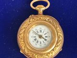 a gold pocket watch with roman numerals on it