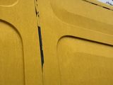 a close up of the side of a yellow van with a hole in it
