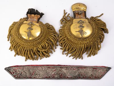une paire de boucles d'oreilles plaquées or et un couteau posés sur un fond blanc