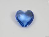 un objet en verre bleu en forme de cœur posé sur une surface blanche