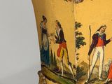 a yellow vase with a picture of a man and a woman on it