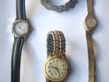trois montres et un bracelet posés sur une surface blanche