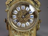 a gold clock sitting on a table with a bird on top of it