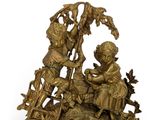 a gold clock with a boy and a girl on it