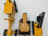 three toy construction vehicles sitting next to each other on a white surface