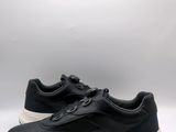 une basket en cuir noir à semelles blanches sur fond blanc