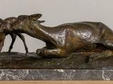 a bronze statue of a goat laying on a rock