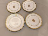 quatre assiettes blanches et dorées, ornées d'une bordure dorée, posées sur une table